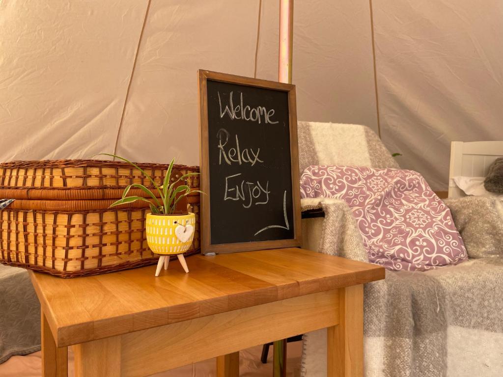 a chalk board on a table with a plant on it at Trevena Cross Glamping in Helston