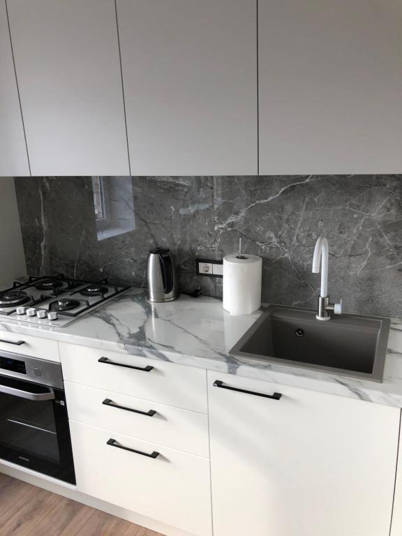 a white kitchen with a sink and a stove at Pilėnų apartamentai in Panevėžys