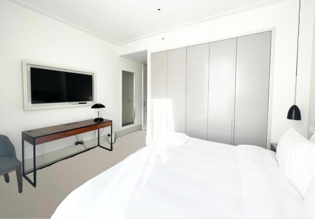 a bedroom with a bed and a desk with a television at Most City Area Pearl Apartment in Dnipro