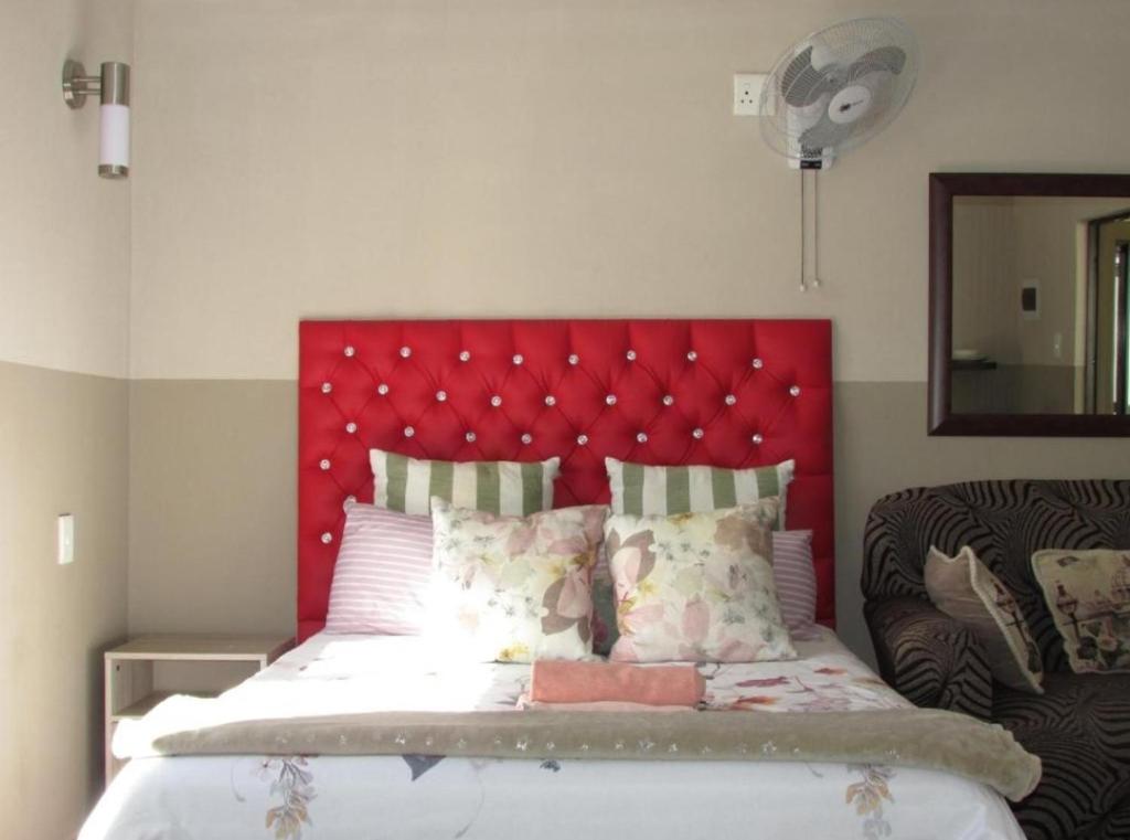 a bed with a red headboard in a bedroom at BelaBela Guesthouse in Bela-Bela
