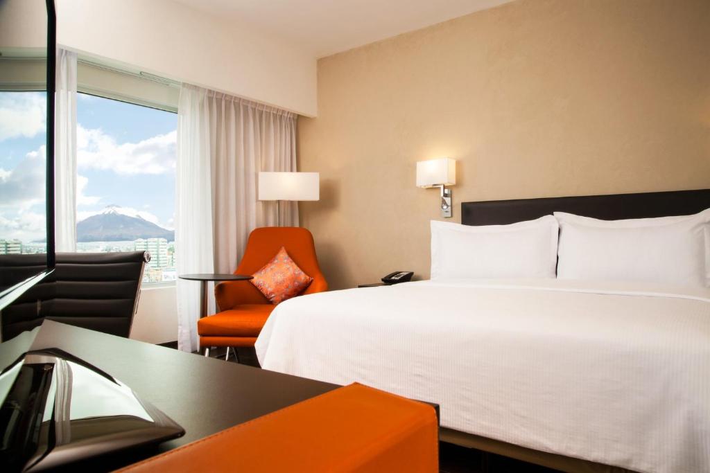 ein Hotelzimmer mit einem Bett, einem Stuhl und einem Fenster in der Unterkunft Fiesta Inn Puebla Las Animas in Puebla