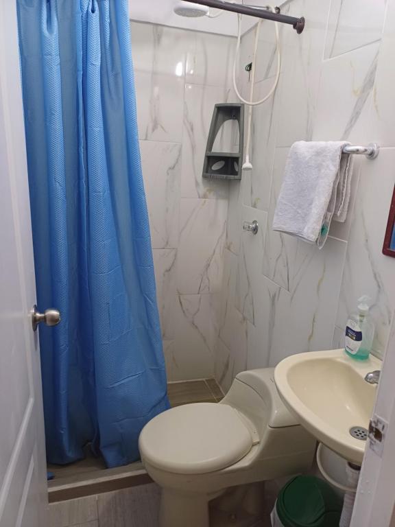 baño con aseo y cortina de ducha azul en APARTAMENTO FAMILIA CAFETERA, en Santa Rosa de Cabal