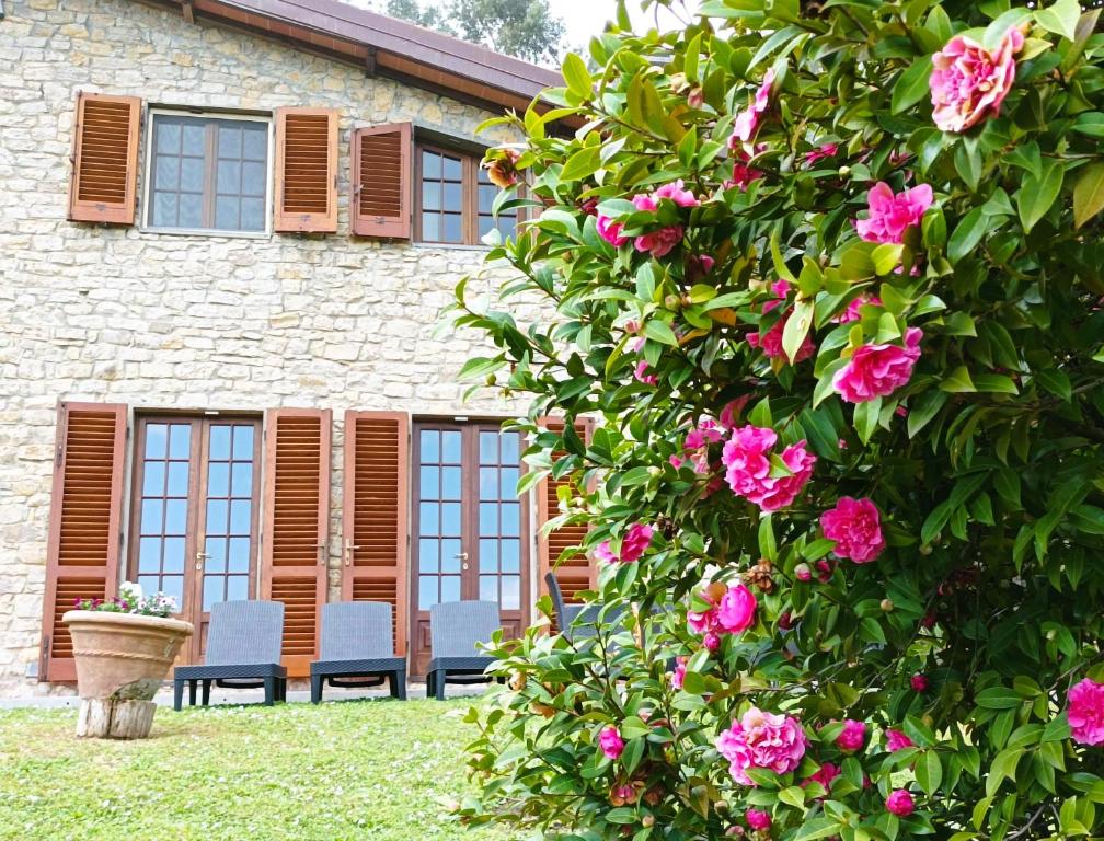 un edificio con sillas y flores delante de él en Villa Camelia Tuscany en Pescia