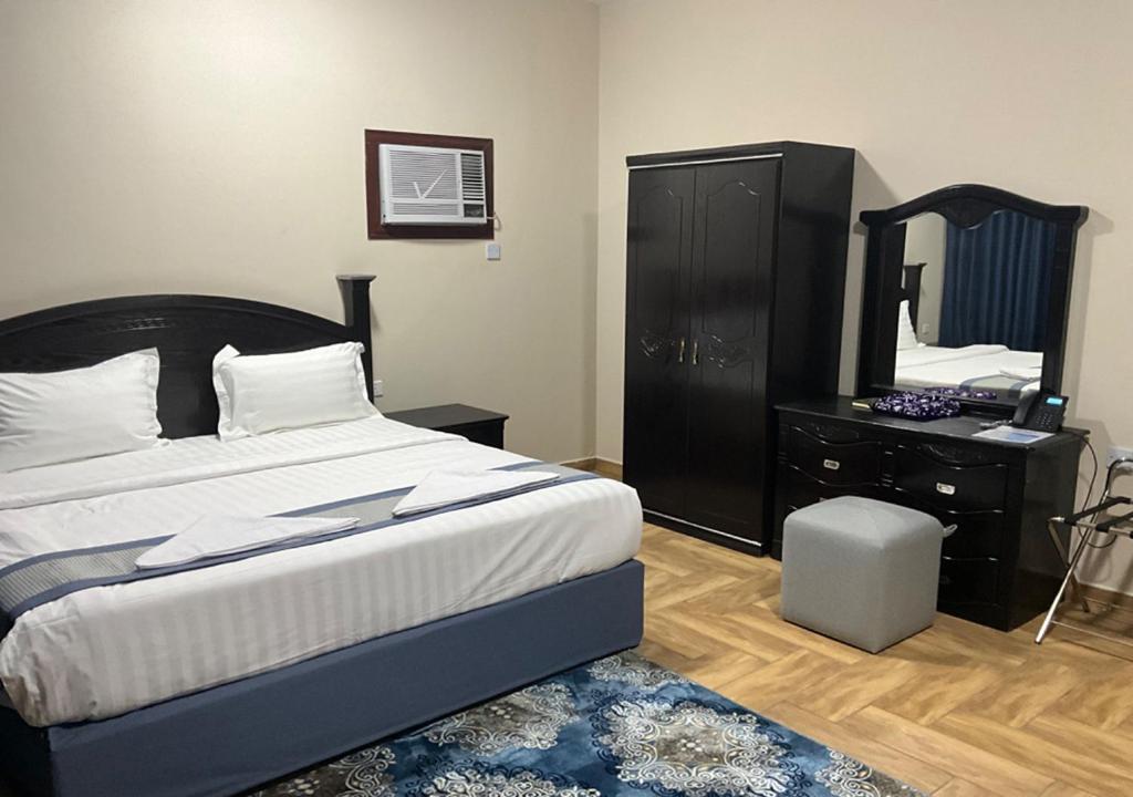 a bedroom with a bed and a dresser and a mirror at Al Baida Suites Al Salam Branch in Al Madinah