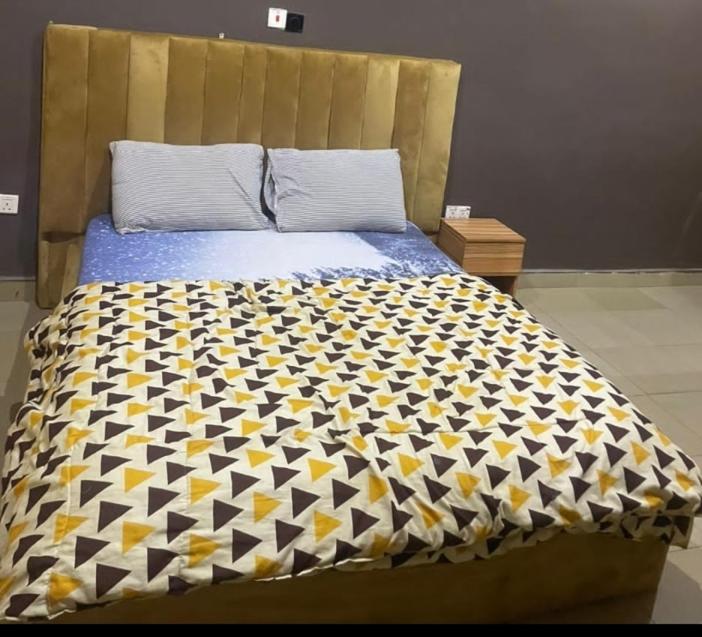a bed with a black and yellow comforter on it at Thilda Hotel and Suites in Alimosho