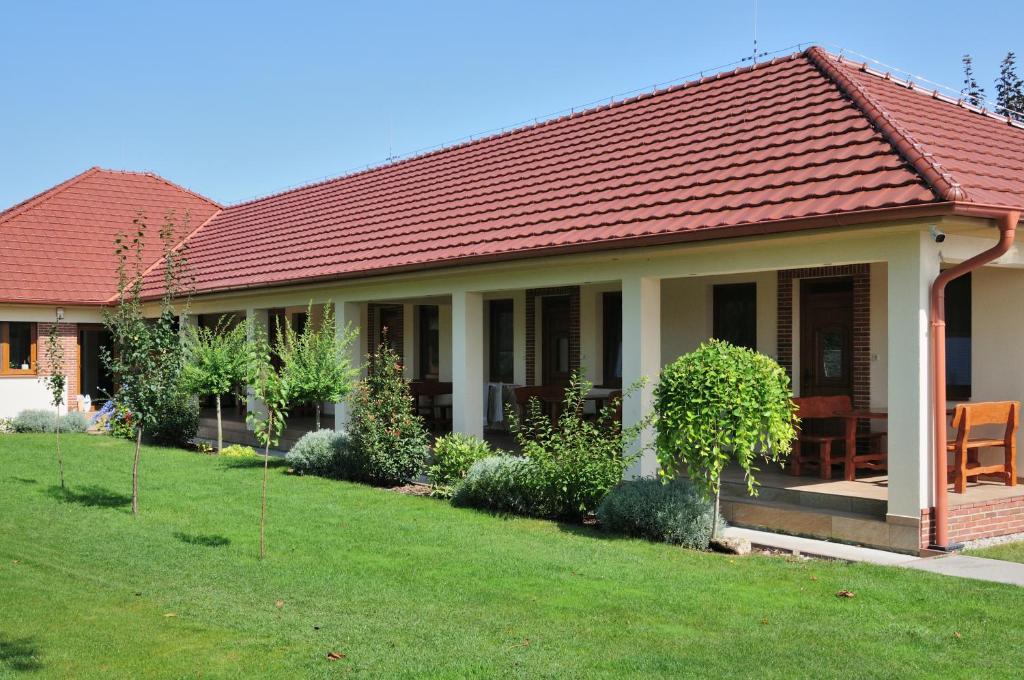 una casa con techo rojo y patio verde en Néró Apartman, en Veľký Meder