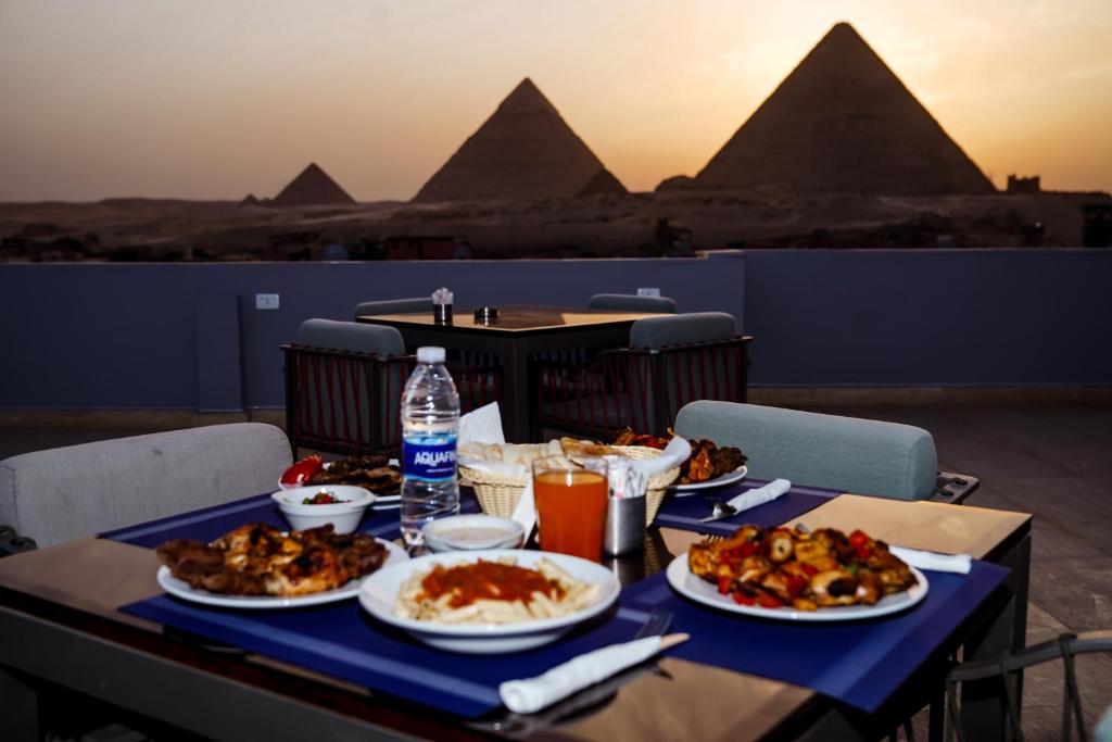 a table with plates of food on it with pyramids at Pyramids Inn in Cairo