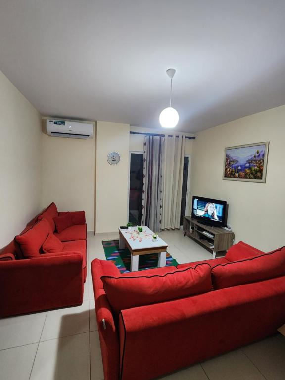 sala de estar con 2 sofás rojos y TV en Lucky's apartment, a place to be, en Pogradec
