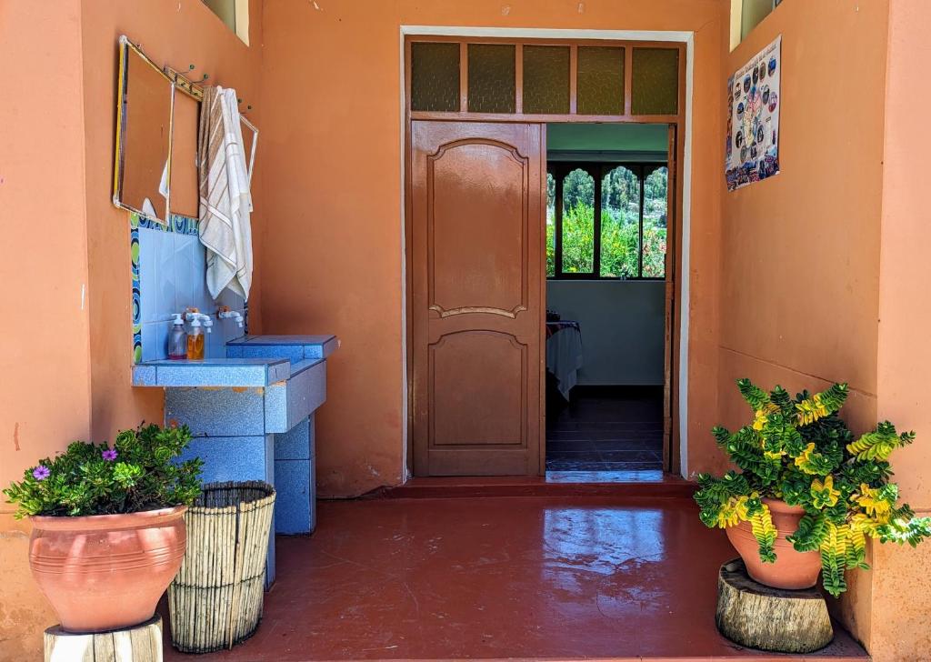 una entrada a una casa con puerta y macetas en Amantani sol Andino en Ocosuyo