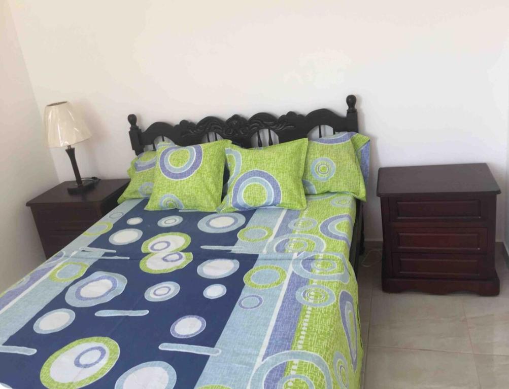 a bed with green and blue sheets and pillows at Casa Bella Salinas in Salinas