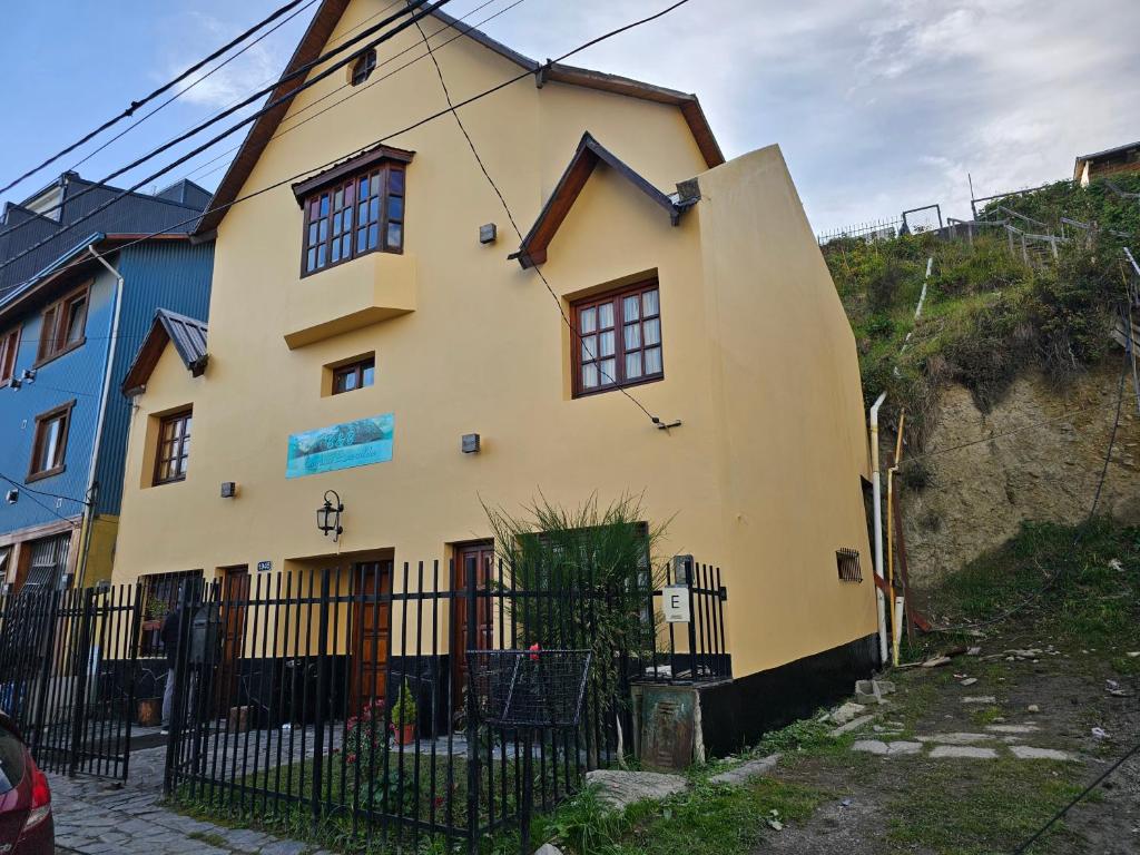 ein gelbes Haus mit einem Zaun davor in der Unterkunft Laguna Esmeralda B&B in Ushuaia