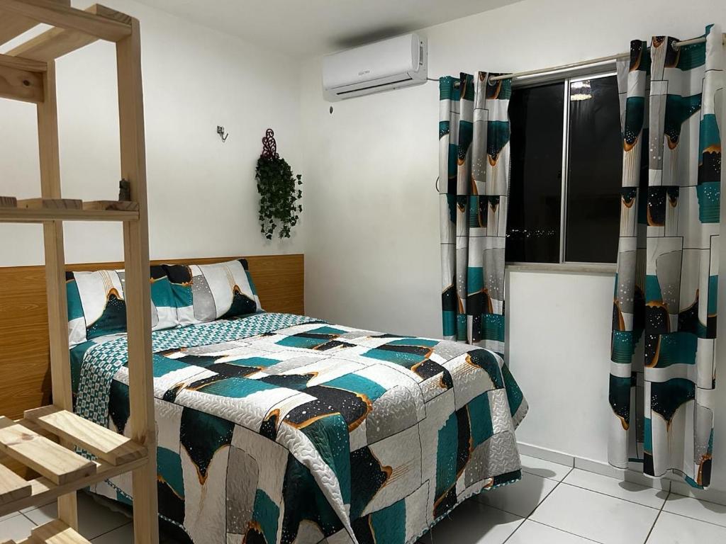 a bedroom with a bed with a comforter and a window at Apto bem localizado est de Ribamar ao lado do shopping in São-José-do-Ribamar