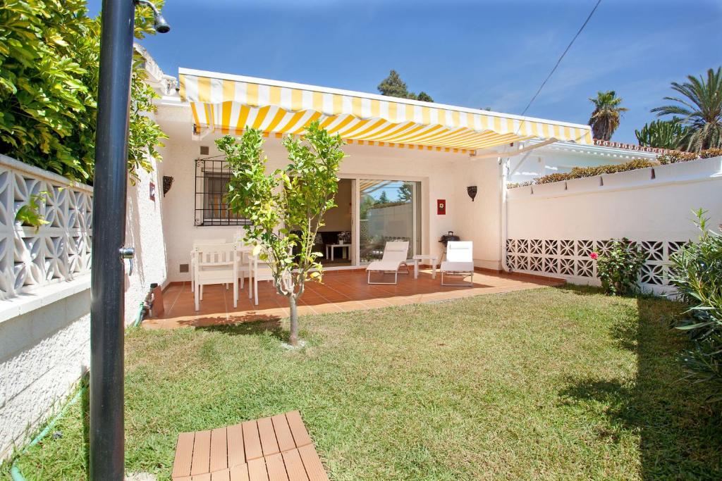 un patio trasero de una casa con toldo amarillo en Casa Progreso Costabella, en Marbella