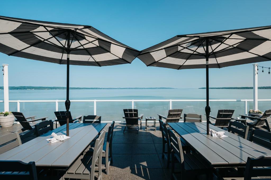 トラバースシティにあるAlexandra Innのビーチでのパラソル付きのテーブル2台と椅子