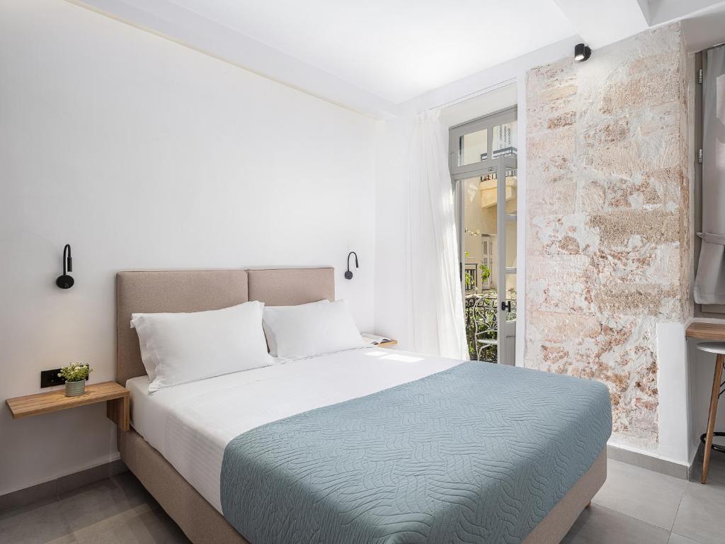 a white bedroom with a large bed and a window at Porto Vecchio in Chania Town