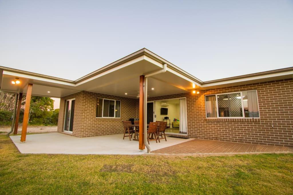 a brick house with a patio with a table and chairs at Seas The Day - pet-friendly house in Agnes Water in Agnes Water