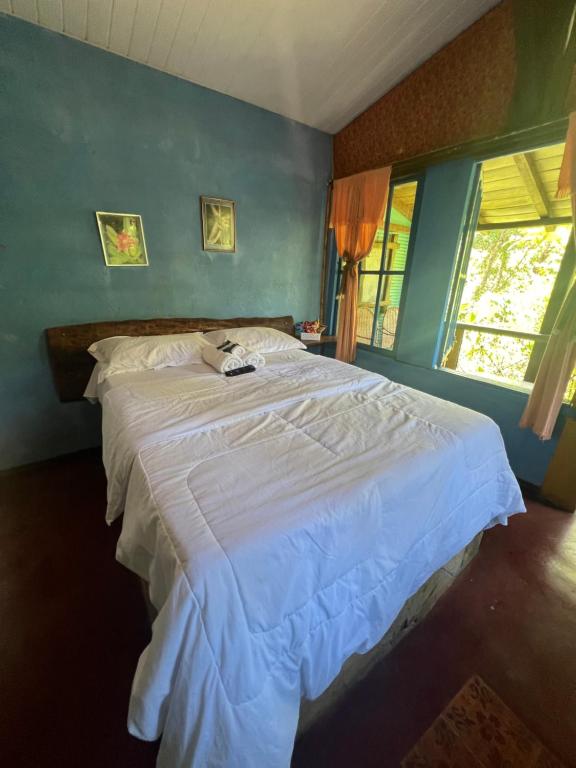 - une chambre avec un grand lit blanc et un mur bleu dans l'établissement Pousada Lua Bonita, à Nova Lima