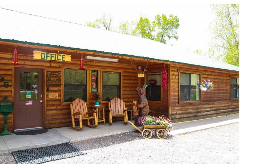 una cabaña de madera con una mesa y sillas frente a ella en Vista Del Rio Lodge en Chama