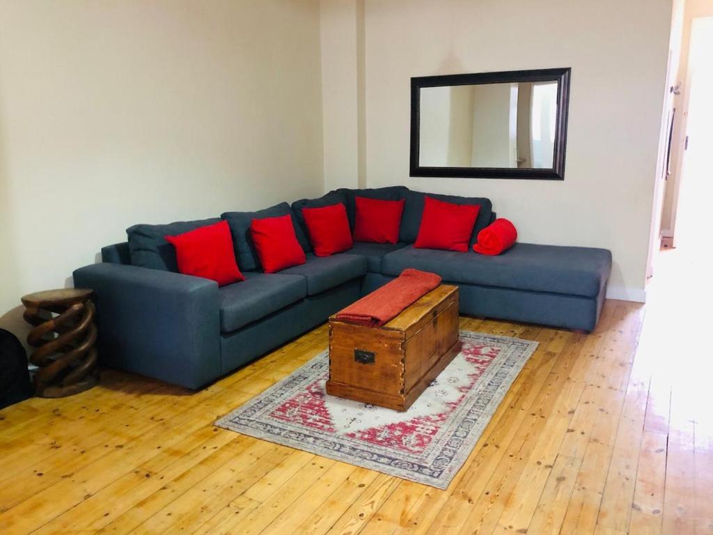 ケープタウンにあるCharming, Central 1 Bed apartmentのリビングルーム(青いソファ、赤い枕付)
