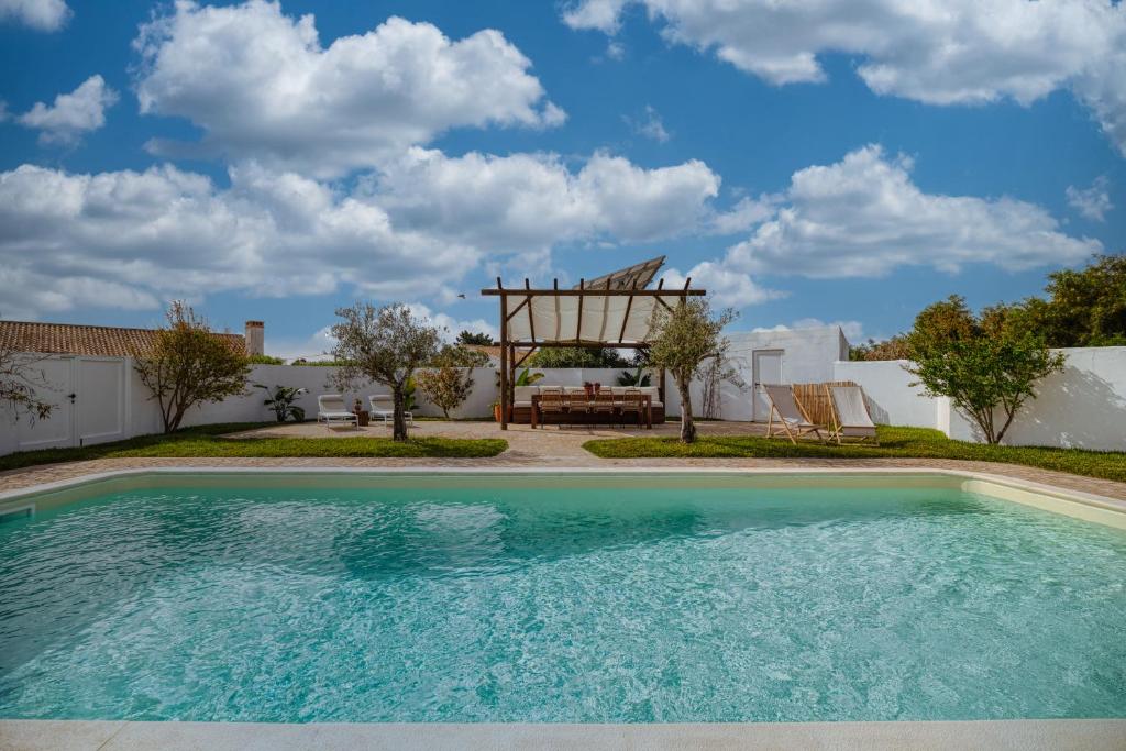 a swimming pool in front of a house with a gazebo at Sunday Morning Guesthouse in Aljezur