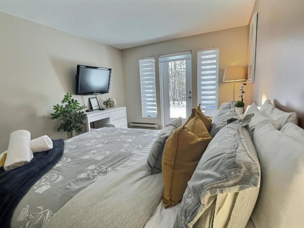 een slaapkamer met een groot bed en een televisie bij The Sunbeam in Mont-Tremblant