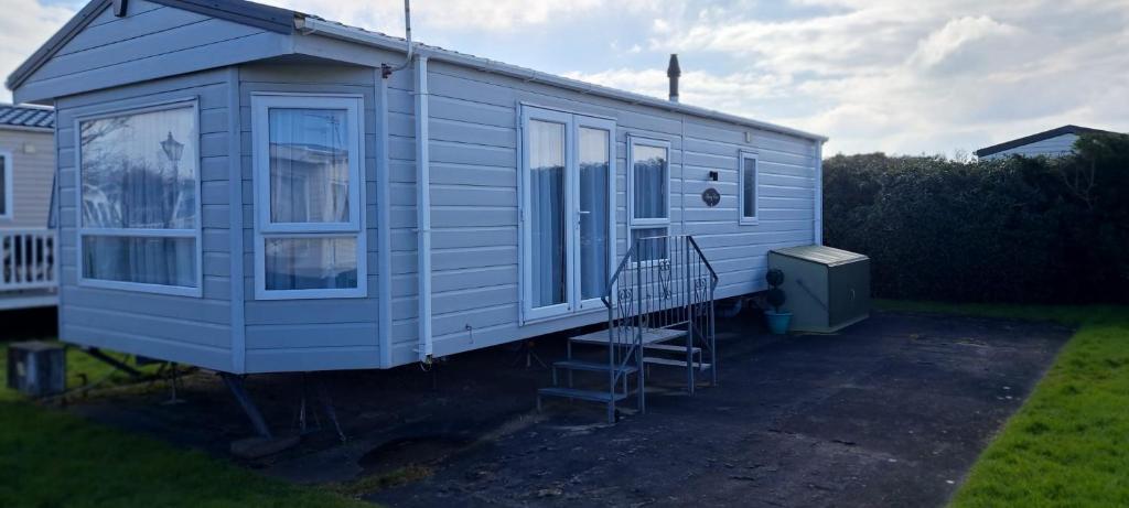 a blue tiny house parked in a yard at Gold star 6 birth caravan in Berrow