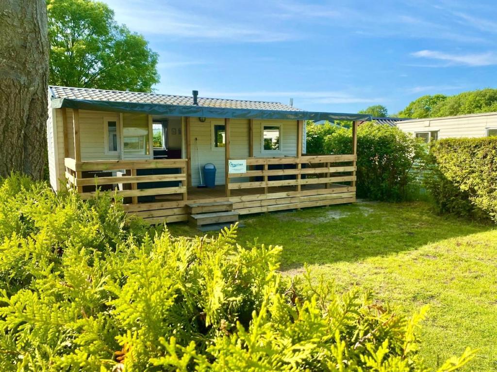 ein kleines gelbes Haus mit einer Holzveranda in der Unterkunft Mobilheim Zuidlaren in Tynaarlo