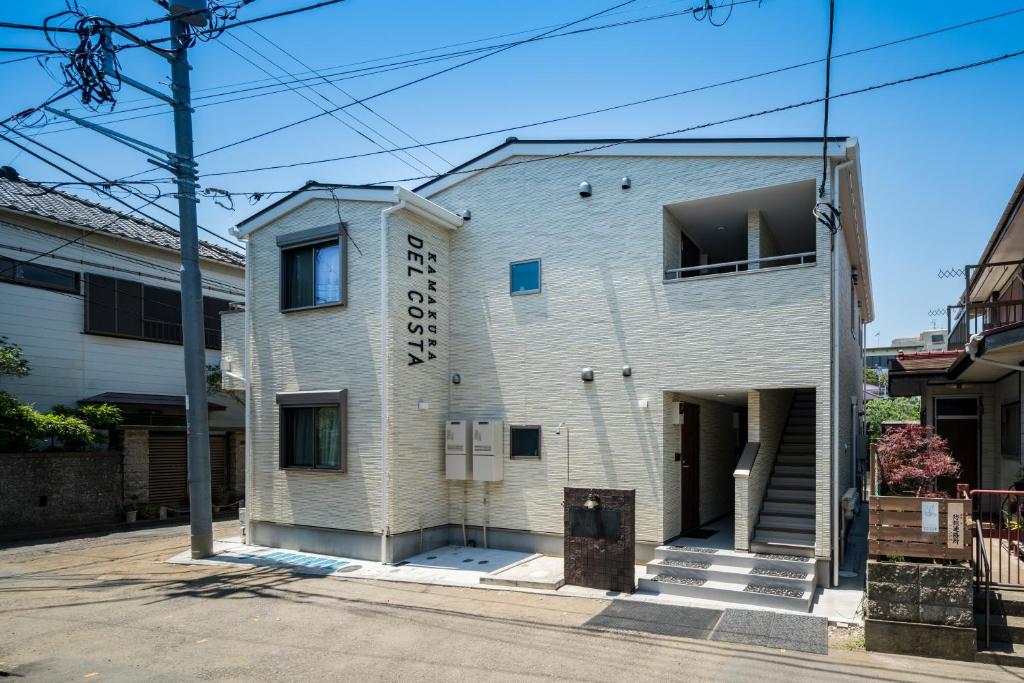 un bâtiment en briques blanches avec un panneau sur celui-ci dans l'établissement KAMAKURA DEL COSTA, à Kamakura