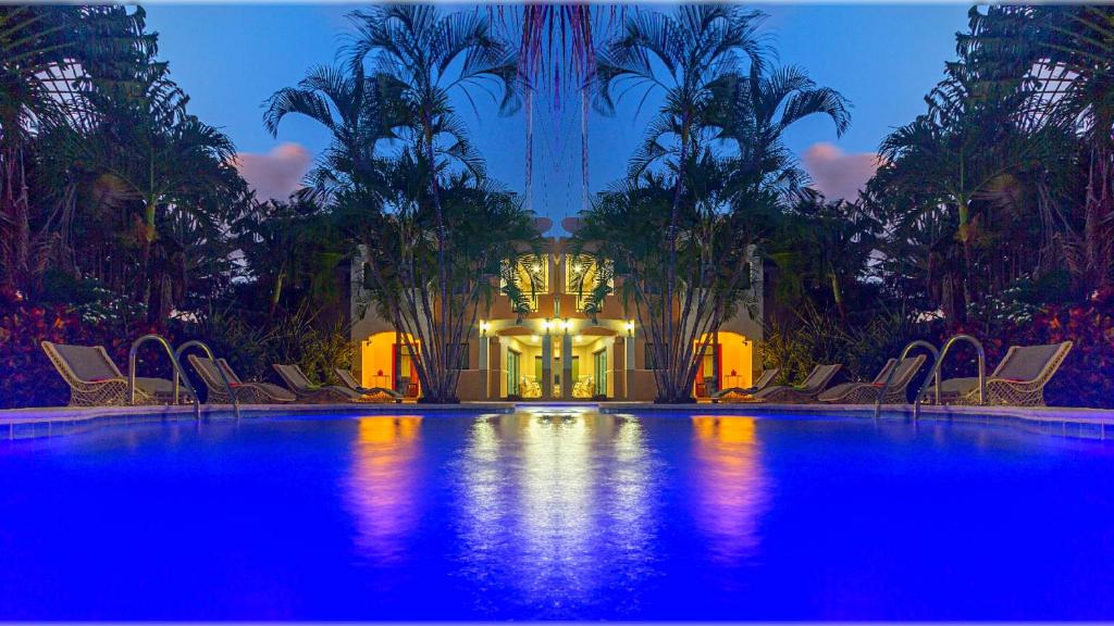 a swimming pool with chairs and palm trees at night at "Villa Infinito"Bani's Exclusive Beachside Mansion in La Noria