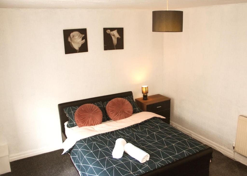 una camera da letto con un letto e due pantofole sopra di AmazenHome - Stylish 3 bed - House of Ebony a Leigh
