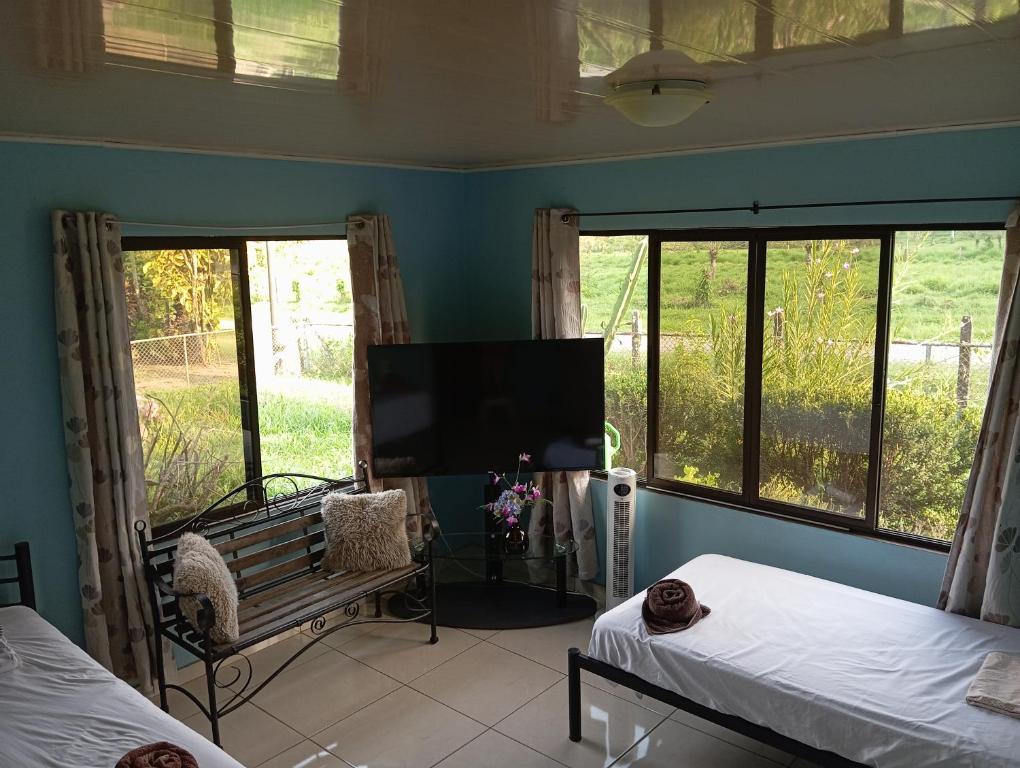 a bedroom with two beds and a flat screen tv at Riverside Home La Fortuna in Tanque