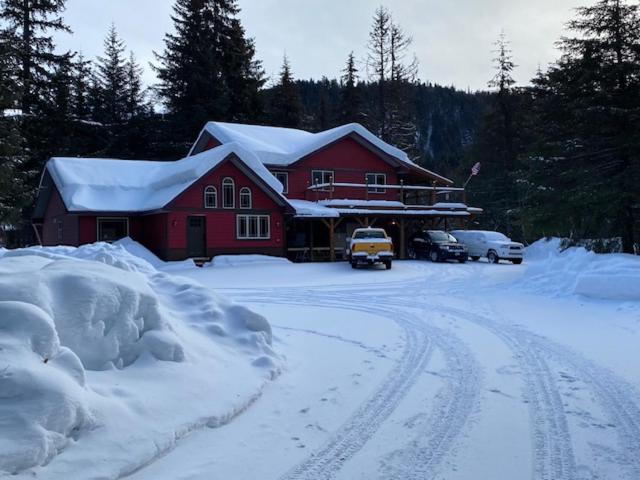 a red house covered in snow next to a road at Resurrection Peaks Lodge in Seward