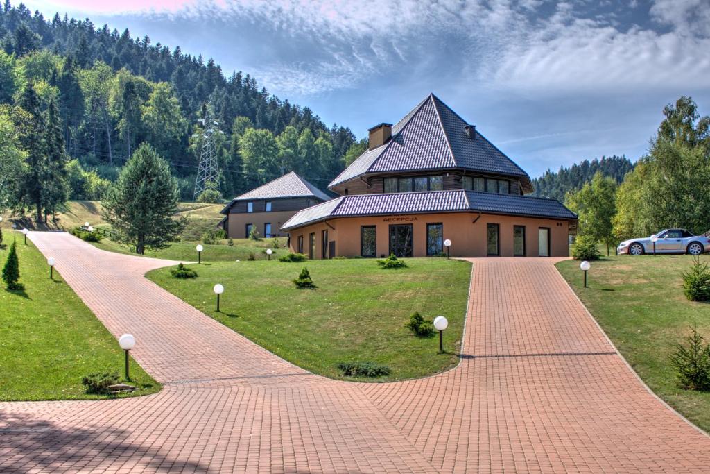 una casa con una pasarela de ladrillo que conduce a un edificio en Puenta Aparthotel en Krynica Zdrój