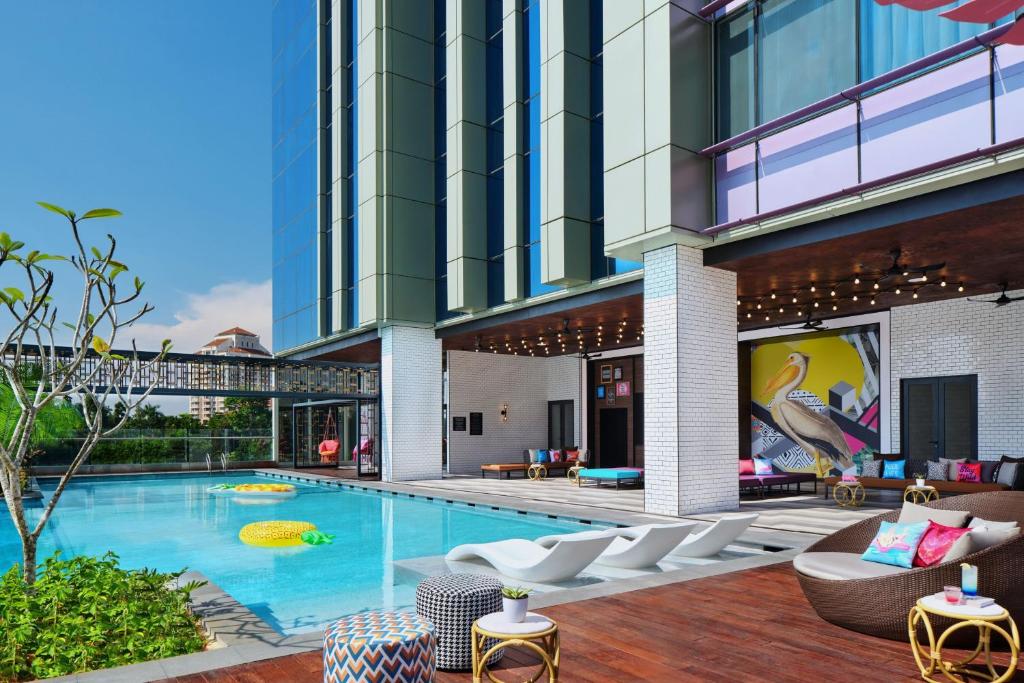 a large building with a swimming pool and chairs at Moxy Putrajaya in Putrajaya