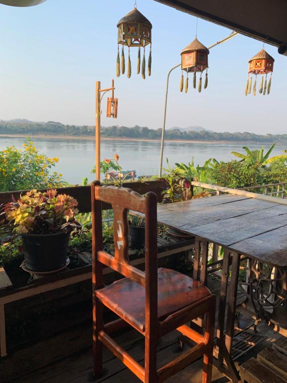a wooden table with a chair and a view of a river at The White House in Chiang Khan
