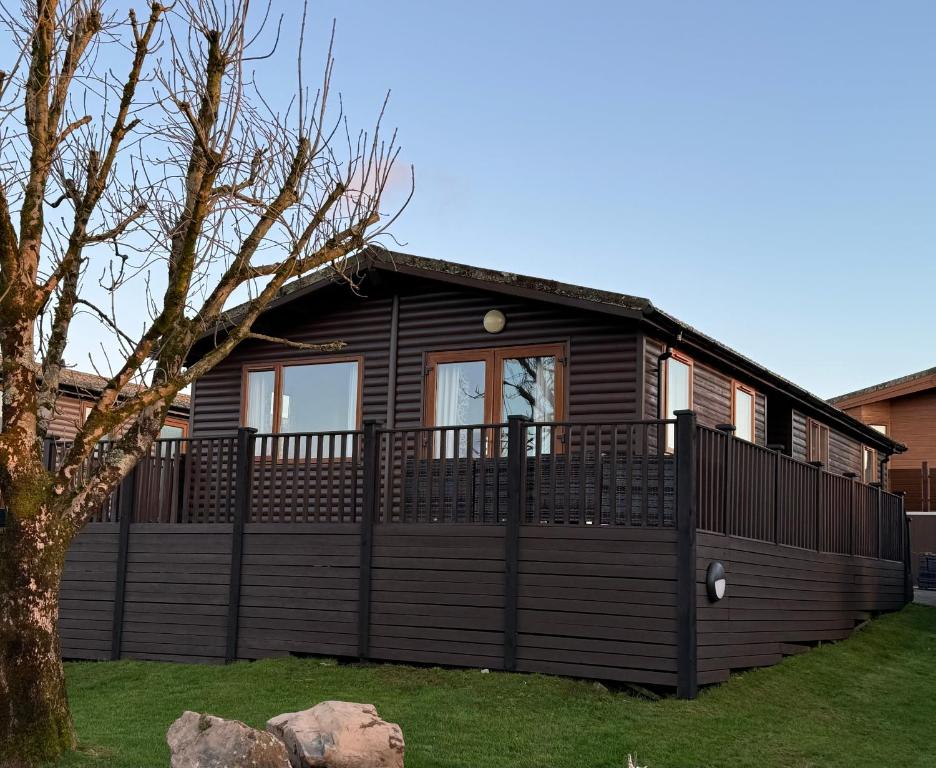 a wooden house with a fence in a yard at Getaway Lodge in Ilfracombe