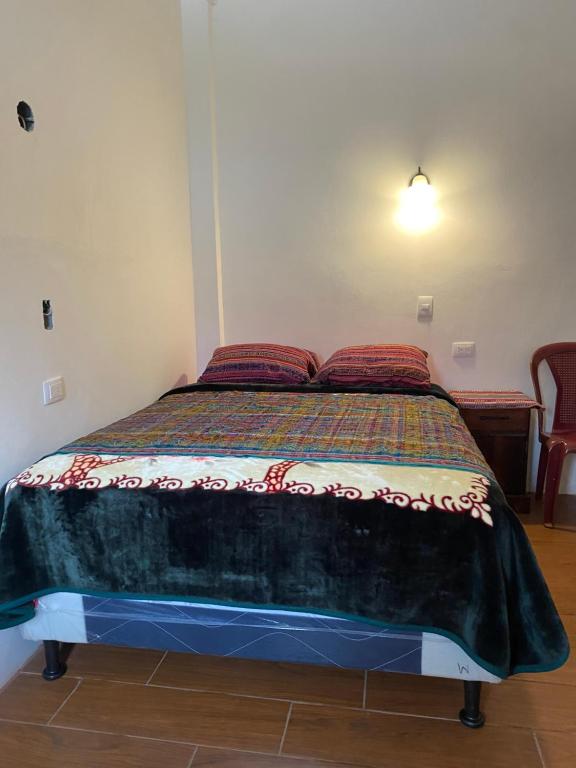 ein Schlafzimmer mit einem Bett mit einer Decke darauf in der Unterkunft “Posada Vicentas” compartir con una familia Tz’utujil in San Juan La Laguna