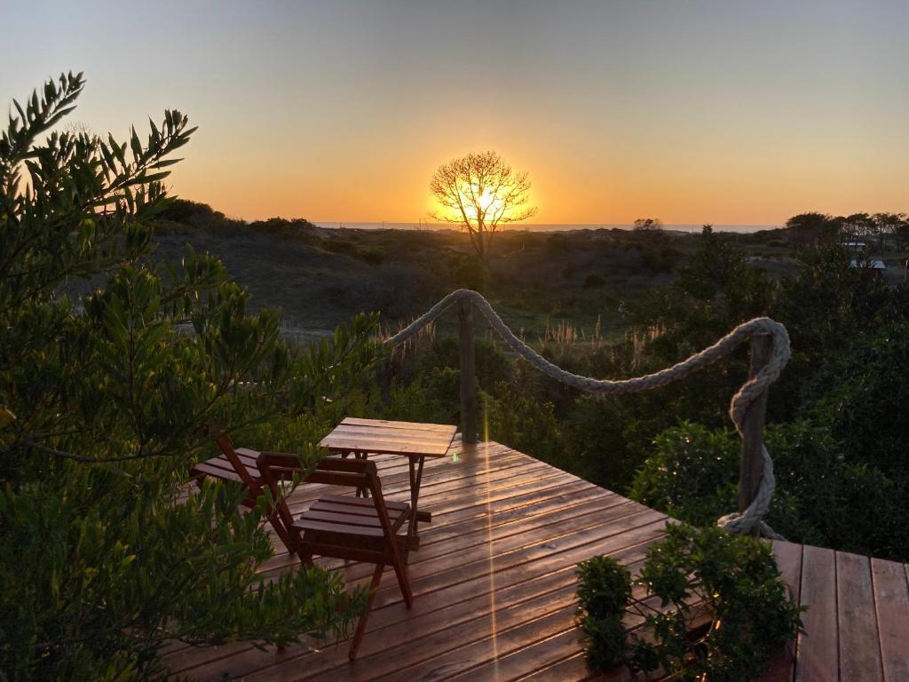 una terraza de madera con mesa y silla al atardecer en La casita, en La Esmeralda