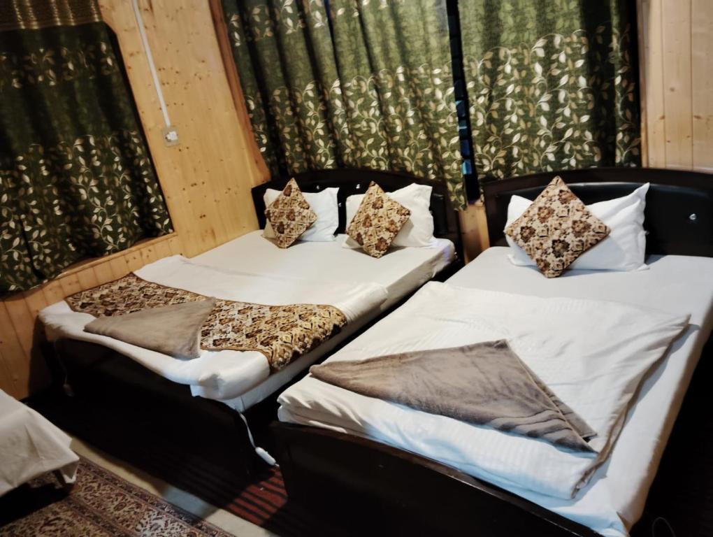 2 Betten nebeneinander in einem Zimmer in der Unterkunft Hotel kaka palace Gurez in Kanzalwan