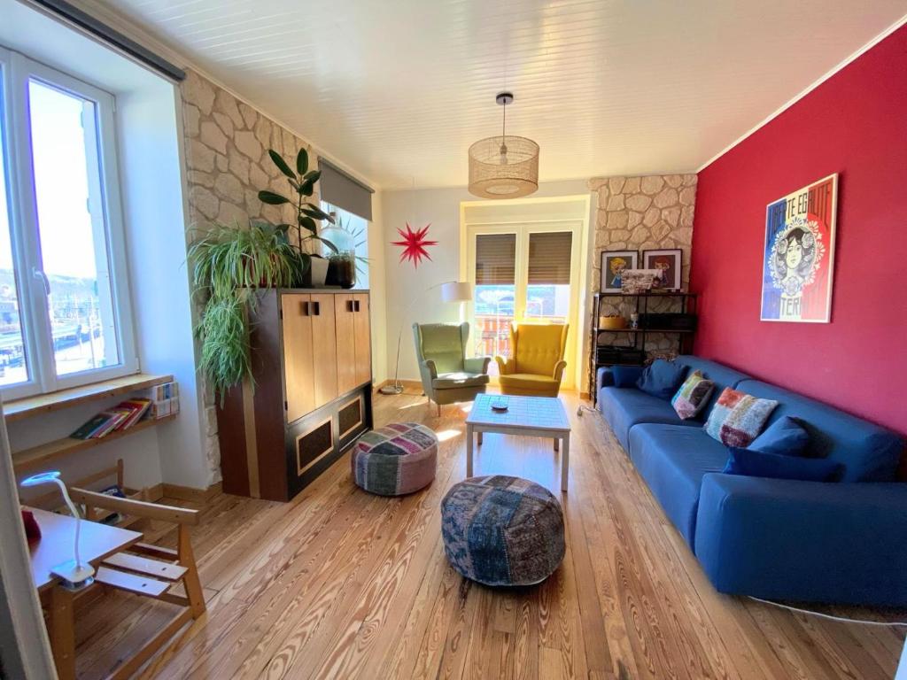 sala de estar con sofá azul y pared roja en Grand appart 115m² avec jardin+parking proche gare en Bellegarde-sur-Valserine