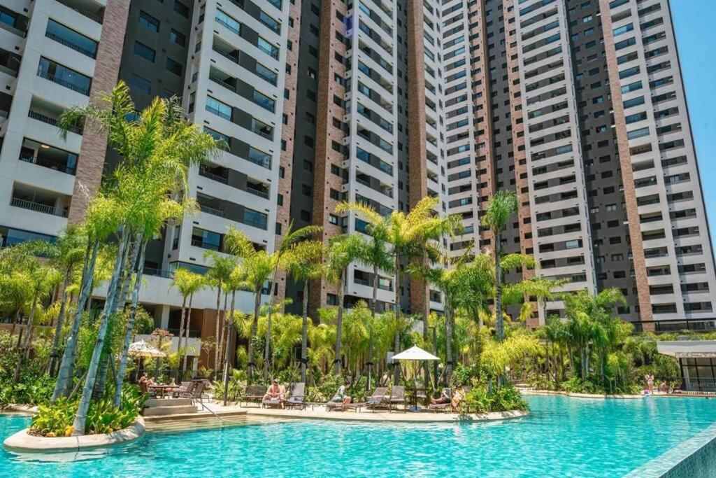 a pool at a resort with palm trees and buildings at Resort, Espaço Verde e Lazer - Centro - São Paulo in Sao Paulo