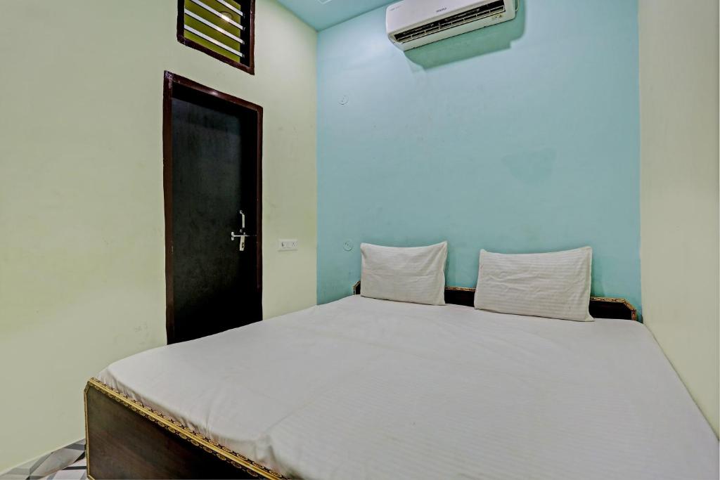 a bedroom with a large white bed with a black door at OYO D Ekant Hotel in Garhi Harsāru