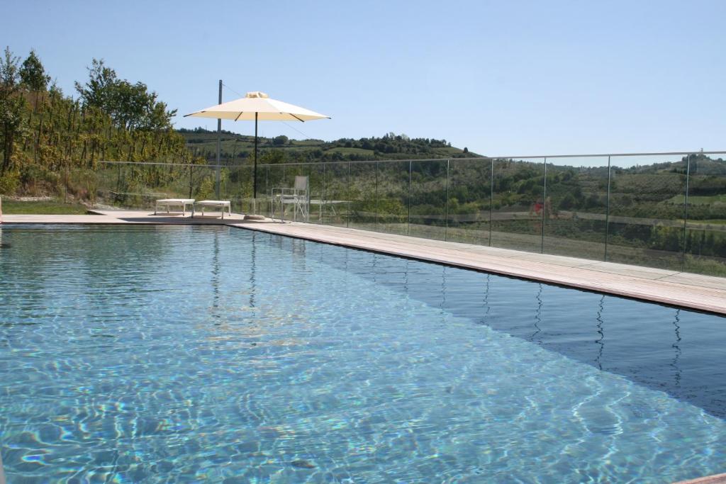 a large swimming pool with an umbrella and a table at Qb Apartments in Montelupo Albese