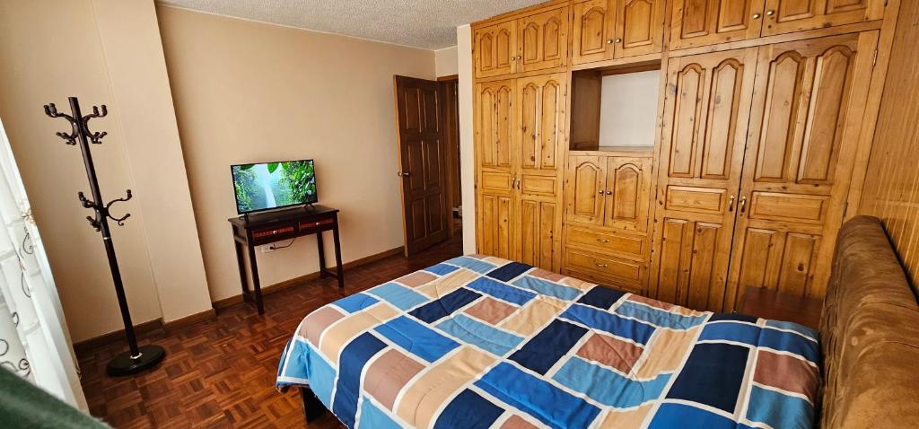 1 dormitorio con 1 cama y TV. en Departamento Bien Ubicado con todo lo necesario en Latacunga