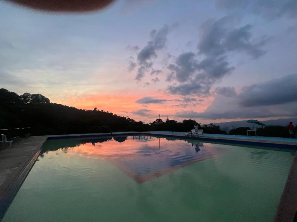 a swimming pool with a sunset in the background at Hotel Campestre Las Marias- El Colegio in El Colegio