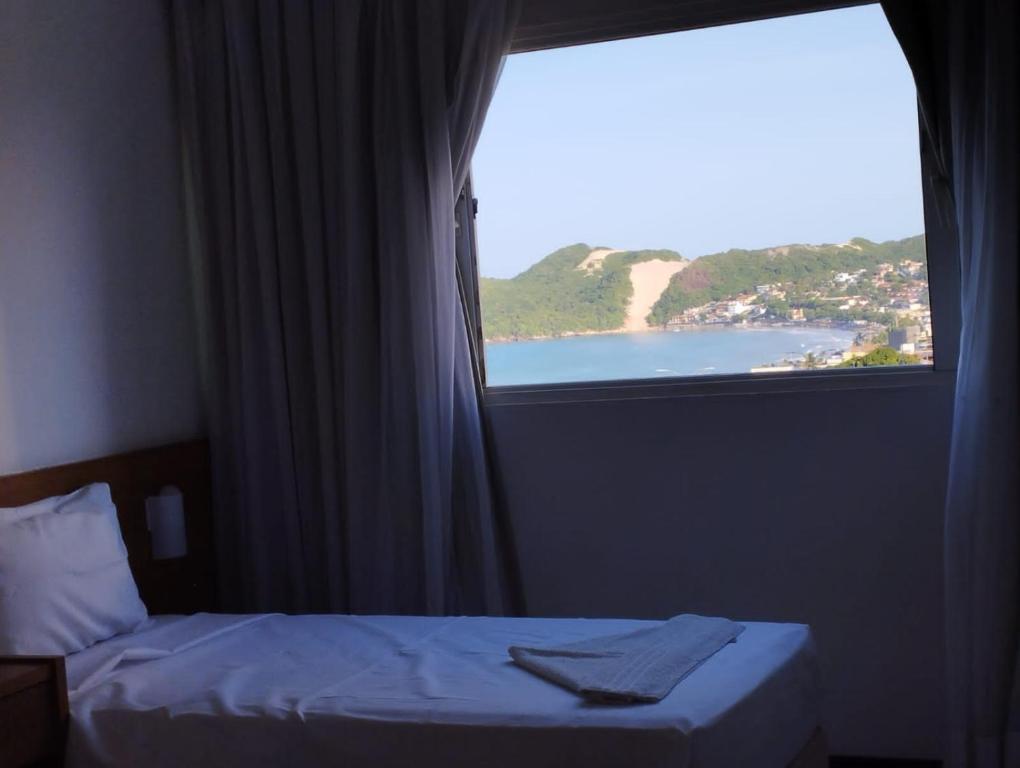 a bedroom with a window with a view of a beach at PONTA NEGRA FLAT APART in Natal