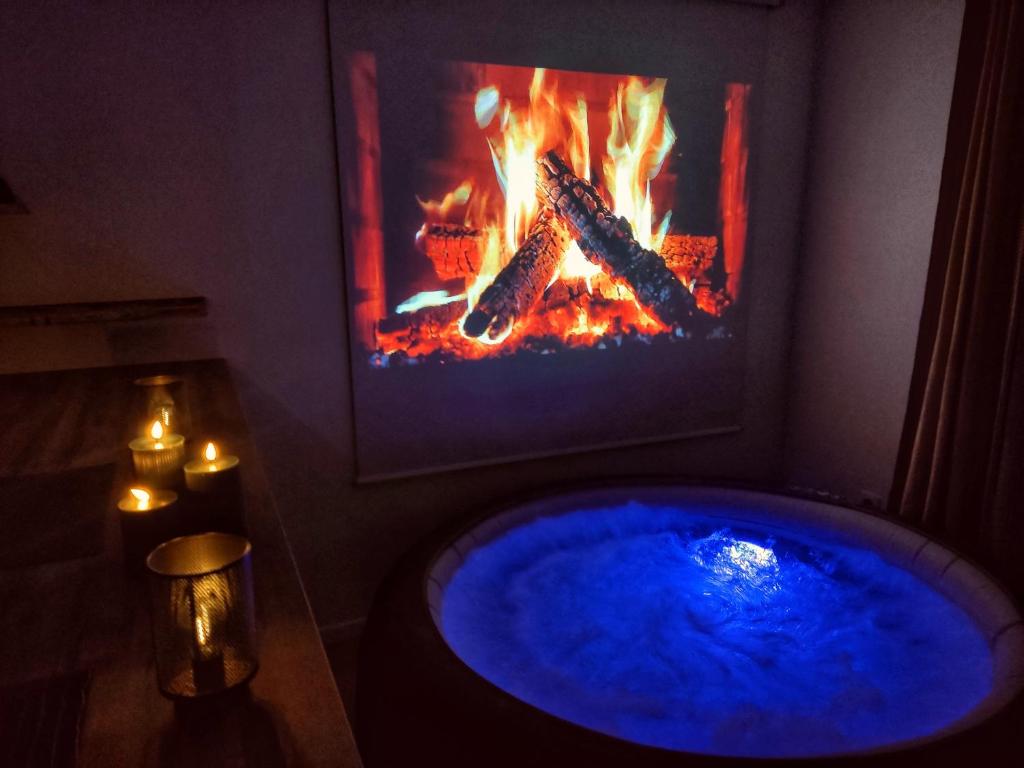 a blue tub in a room with a fireplace at Le nid de l'Almont jacuzzi privatif, private jacuzzi Hot Tub near Olympic Games MELUN in Melun