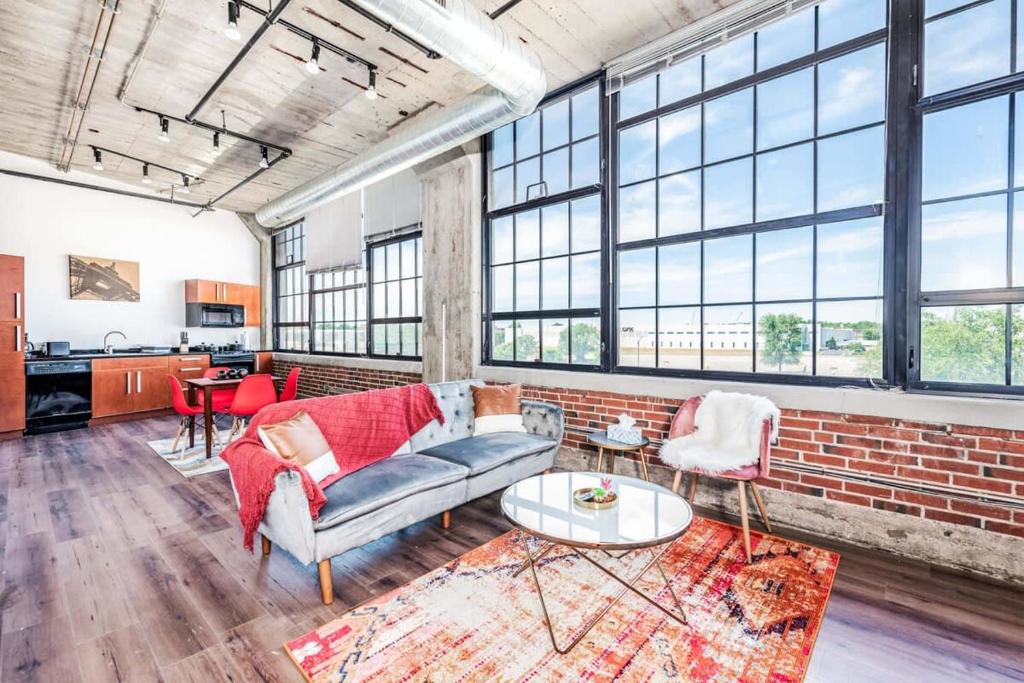 a living room with a couch and a brick wall at Architect's Stunning loft by CozySuites in Saint Louis