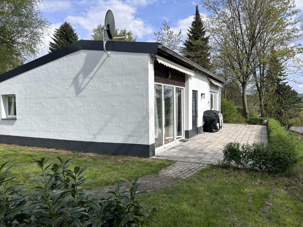 ein kleines weißes Gebäude mit einer Einfahrt auf einem Hof in der Unterkunft Renoviertes Ferienhaus in Husen mit Terrasse und Sauna in Lichtenau