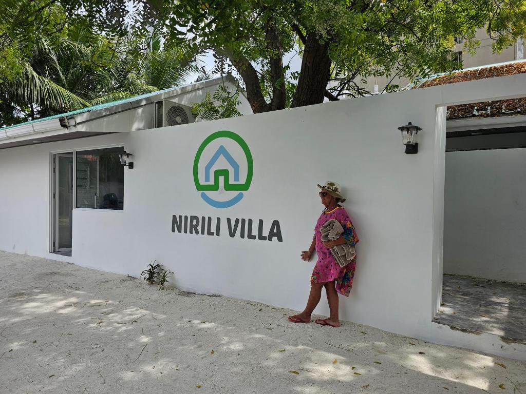 a woman standing in front of a white wall at Nirili Villa in Dhiffushi